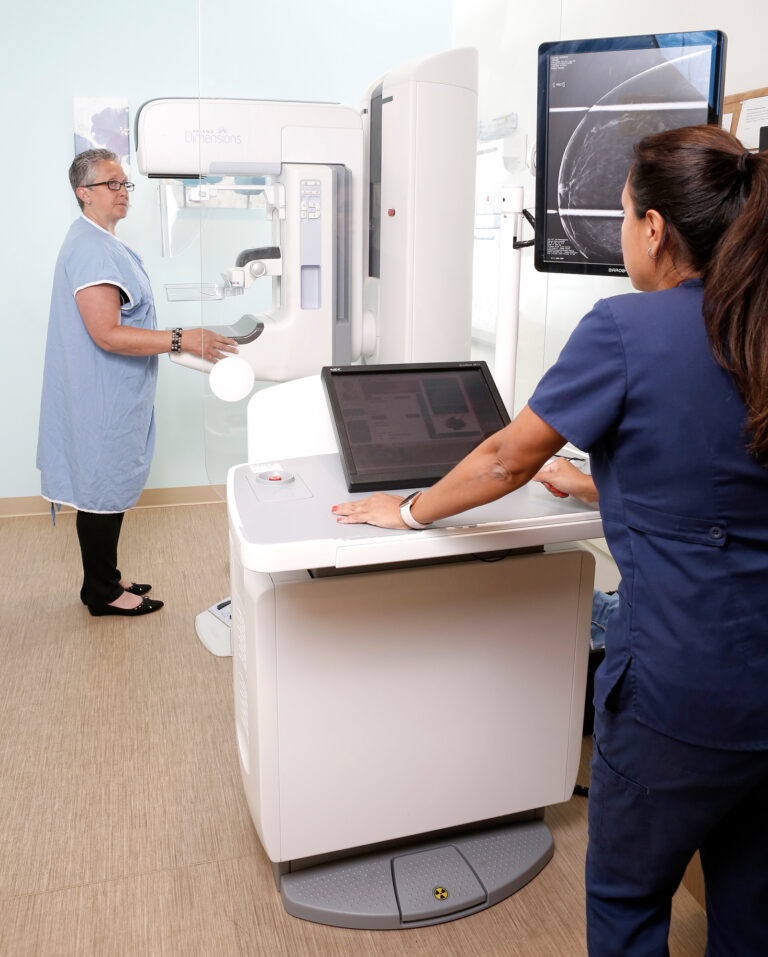Radiologist preparing female patient for mammogram